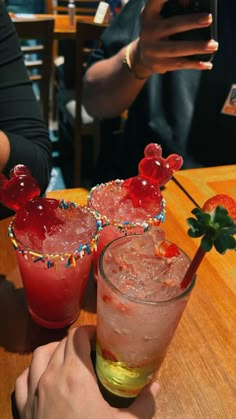 two people sitting at a table with drinks in front of them and one holding a cell phone