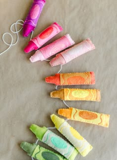 four different colored rolled candys sitting on top of a piece of paper next to a string