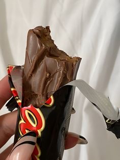 a hand holding a chocolate bar with a knife sticking out of it's wrapper