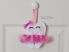 a tooth shaped ornament hanging on a door with pink and white tulle