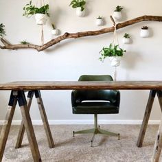 a wooden table sitting in front of a white wall with hanging plants on the wall