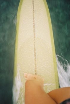 a woman is sitting on a surfboard in the water with her feet propped up