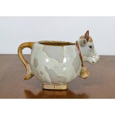 a ceramic cow mug sitting on top of a wooden table