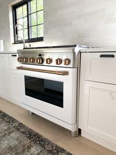 a white stove top oven sitting inside of a kitchen next to a rug and window