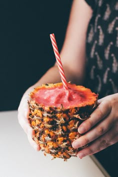 a person holding a pineapple drink with a straw in it's hand and a candy cane sticking out of the top