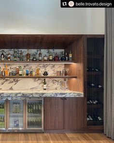 a bar with lots of bottles and glasses on the top shelf, along with shelves full of liquor