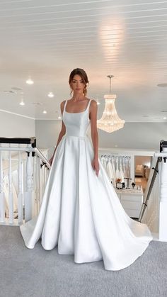 a woman in a white wedding dress standing next to a chandelier and stairs