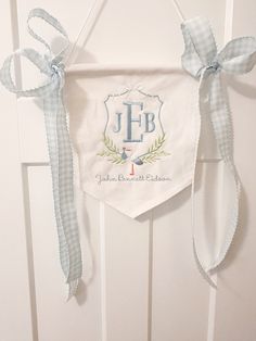 a white door hanger with a monogrammed initial and ribbon hanging from it