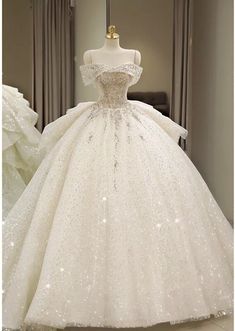 a white ball gown with sequins and beading on the skirt is displayed in front of a mannequin