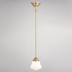 an antique brass ceiling light with a white glass shade hanging from it's side