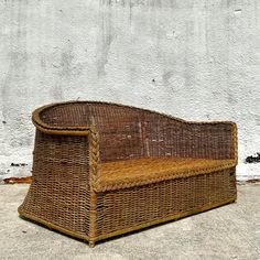 a wicker bench sitting in front of a white wall