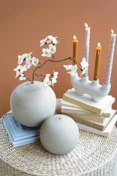 two white vases with candles and books on a wicker table