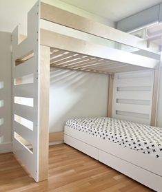 a white bunk bed sitting next to a wooden floor