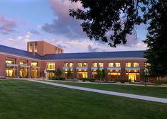 a large brick building with many windows and lights on it's sides at dusk