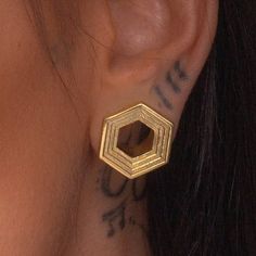 a close up of a person's ear with tattoos on her left ear and behind the ear is a gold hexagon