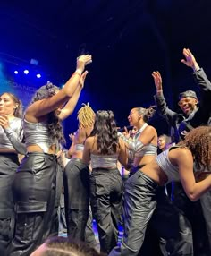 a group of people standing on top of a stage with their hands in the air