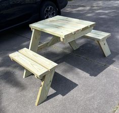 a wooden picnic table sitting next to a parked car