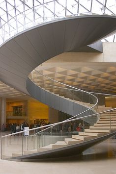 the inside of a building with stairs and people walking up it's sides, in front of a glass ceiling