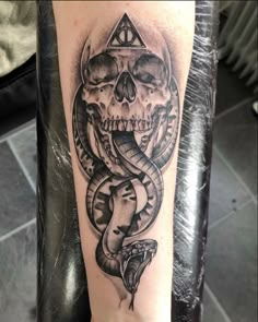 a black and white tattoo on the arm of a person with a snake around it