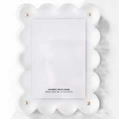 a white frame with scalloped edges and pearls on the edge is shown in front of a white background