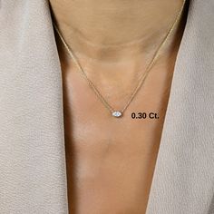 a woman wearing a necklace with a heart shaped diamond on the back of her chest