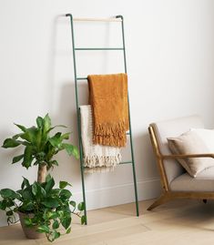 a towel rack next to a chair and potted plant