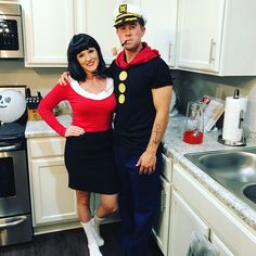 a man and woman dressed up in costumes standing next to each other near a kitchen sink