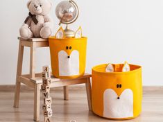 a teddy bear sitting on top of a chair next to two bins