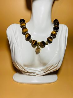 Add a touch of elegance to your outfit with this stunning gemstone necklace designed for women. Featuring 16mm Tigers Eye gemstone beads adorned with a beautiful gold-plated crystal flower wheel, this necklace is perfect for adding a pop of color and sophistication to any look. Handcrafted with precision and attention to detail, this unique piece is sure to make a statement wherever you go. this necklace exudes charm and sophistication. Perfect for everyday wear or special occasions, this piece Amber Polished Beads Necklace For Gifts, Elegant Crystal Necklaces With Large Beads As A Gift, Elegant Crystal Necklace With Large Beads For Gifts, Meditation Necklaces With Round Beads And Stones, Gold Necklaces With Round Stone Beads, Elegant Amber Beaded Necklaces With Large Beads, Amber Jewelry With Large Beads For Gifts, Elegant Amber Jewelry With Polished Beads, Beaded Round Pendant Necklaces For Healing