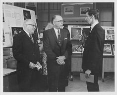 three men in suits are talking to each other