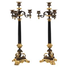 two black and gold candelabra with candlesticks on each side,