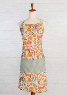 an apron on a mannequin with oranges and leaves printed on the front