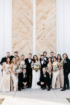 a group of people standing next to each other in front of a wooden wall and door