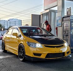 a yellow car parked in front of a gas station with a man standing next to it