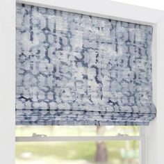 a blue and white patterned roman blind in a window