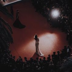 a woman standing in front of an audience at a fashion show wearing a long white dress