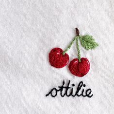 two cherries are embroidered onto the back of a white shirt that says ottilie