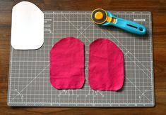 a pair of pink mitts sitting on top of a cutting board