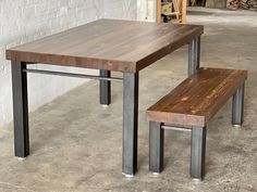 a wooden table and bench in a room with exposed brick walls, concrete flooring and steel legs