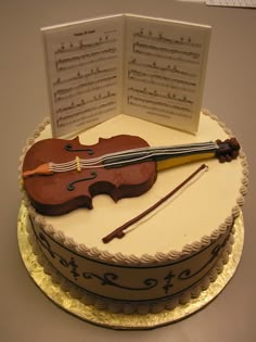 there is a cake that has a violin on it and sheet music in the background