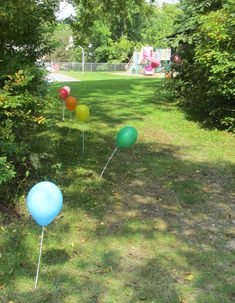 several balloons are in the grass near some trees