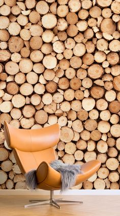 an orange chair sitting in front of a pile of logs wallpapered with wood