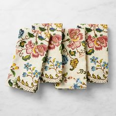 four napkins with floral designs on them sitting on a marble countertop next to each other