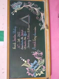 a chalk board with writing on it in front of a pink wall