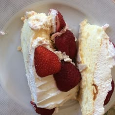 two pieces of cake on a plate with strawberries and whipped cream, one slice cut in half