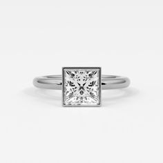 Princess cut diamonds exude modern elegance when set in a bezel setting. This setting surrounds the diamond with a sleek metal rim, securing it firmly while emphasizing its square shape and dazzling facets. The bezel setting not only protects the princess cut diamond from everyday wear but also enhances its brilliance by minimizing distractions and focusing attention on its clean lines and geometric precision. Perfect for those who appreciate a blend of contemporary style and practical design in their jewelry, princess cut diamonds in a bezel setting showcase a sophisticated allure that is both refined and durable. Ring shown is 2 ct diamond.