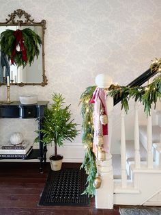 christmas decorations on the banisters and stairs in a living room decorated with greenery