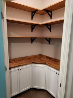 an empty pantry with white cabinets and wood counter tops