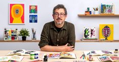 a man sitting at a table in front of art work