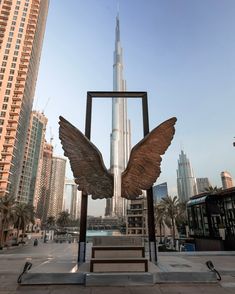 a statue of an angel with wings in front of a cityscape and skyscrapers